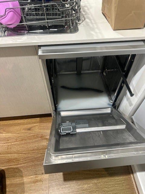 The drain area of a dishwasher showing food debris build-up.